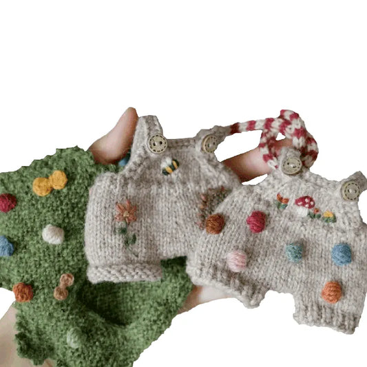 Knitted toys with colorful pom-poms held by a hand on a white background