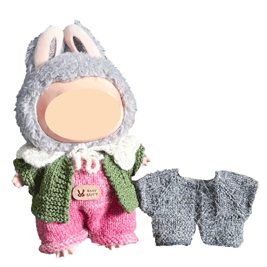 Toy figure with a gray outfit, green jacket, pink pants, and a small gray sweater on a white background.