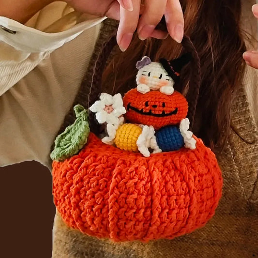 Handmade crochet pumpkin with small plush characters inside, held by a person.