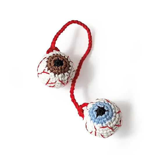 Crocheted eye ball toys with red strings on a white background