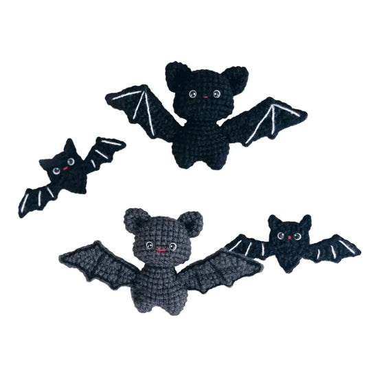 Four black crocheted bat toys on a white background