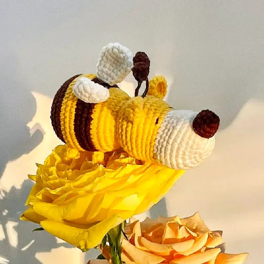 Handcrafted crochet dog bee pattern plush in yellow and brown on a yellow rose