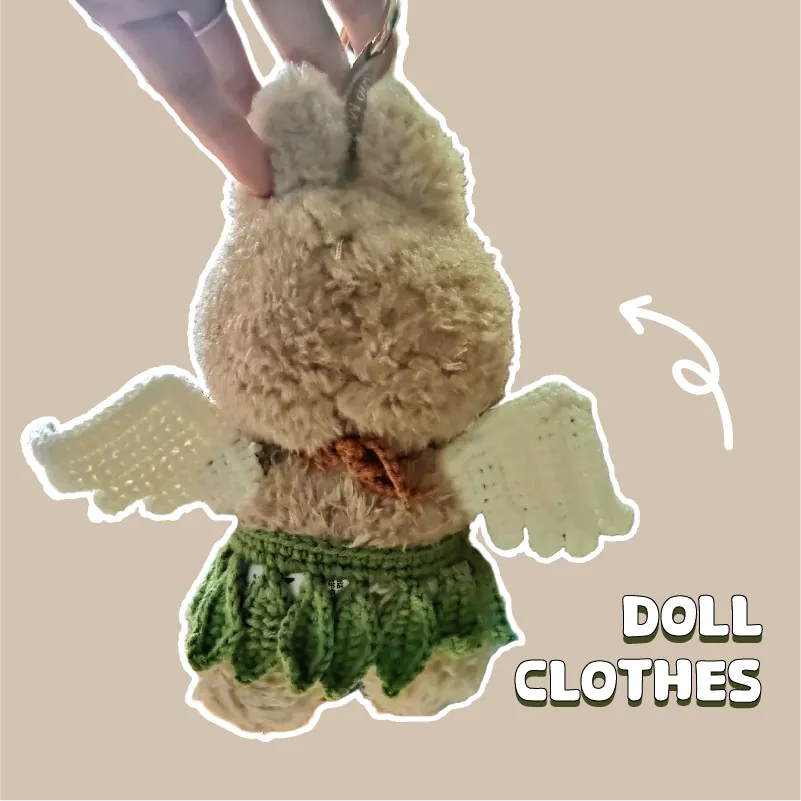 Plush doll wearing a green Beginner Crochet Doll Outfit with white wings held by hand