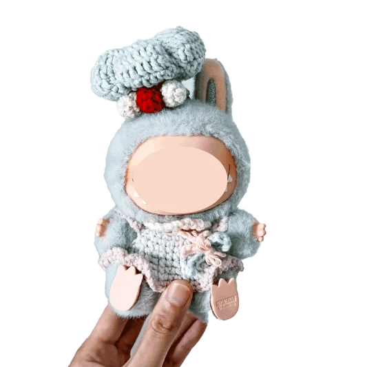 Hand holding a doll dressed in a gray chef costume crochet pattern for dolls with a chef hat and pink details
