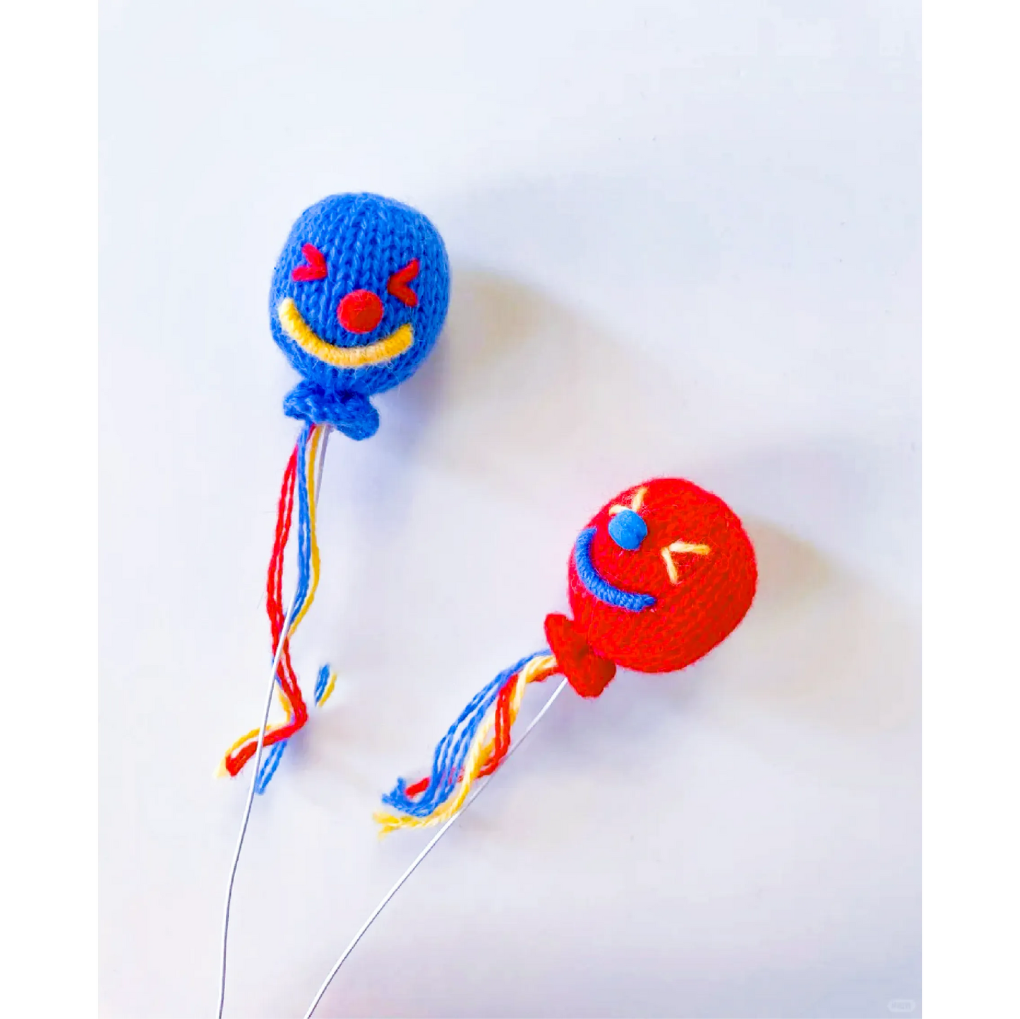 Two colorful crocheted clown heads with tassels using the Circus Clown Crochet Pattern by redbook