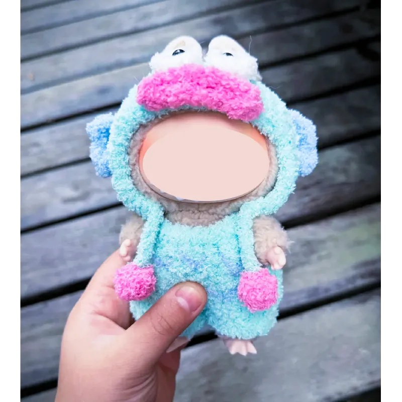 Hand holding a plush toy wearing a colorful clown fish crochet pattern outfit with blue and pink details