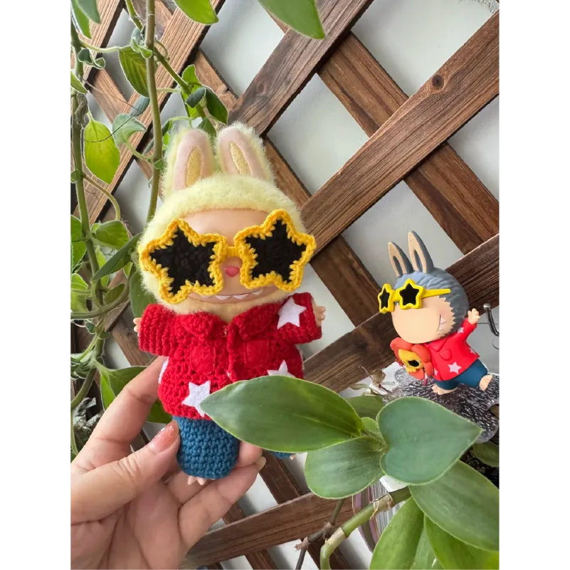 Collectible doll crochet design wearing yellow star-shaped sunglasses and a red hoodie with white stars
