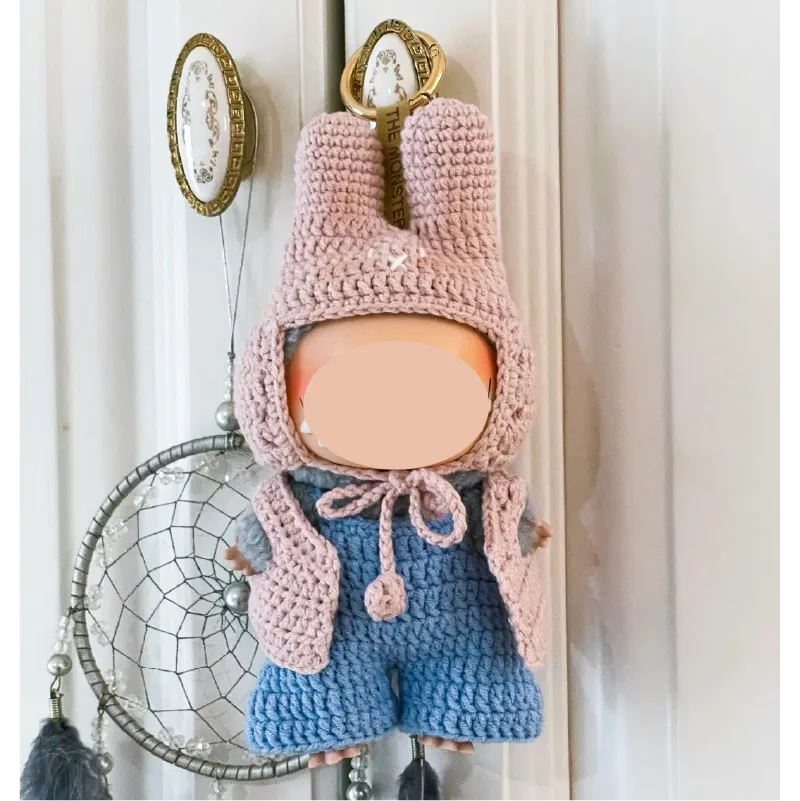 Handmade crochet keychain doll wearing a pink bunny hat and blue outfit by The Knit Krazy