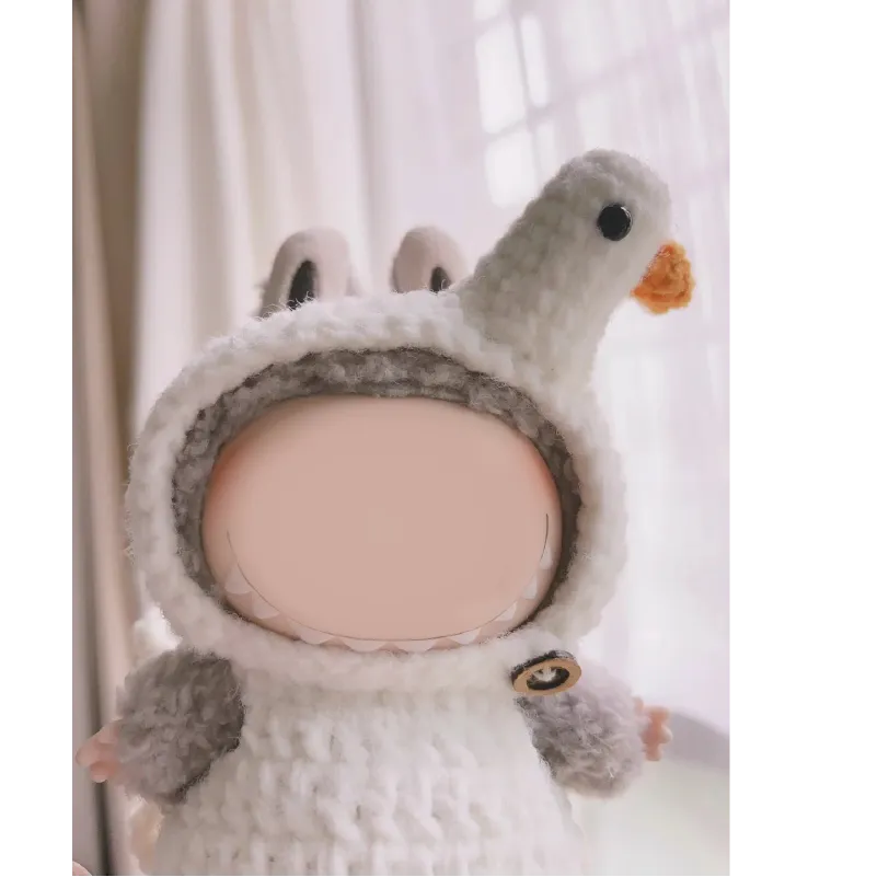 Cute doll wearing a handmade crochet goose outfit pattern with a white body and orange beak details