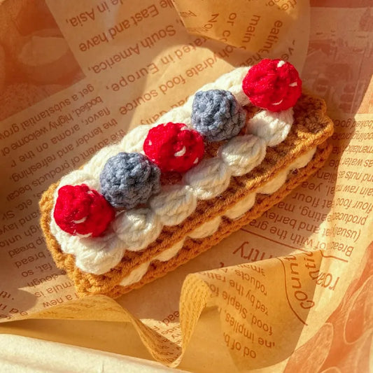 Crochet Napoleon cake replica with white cream and red and purple berry decorations using crochet Napoleon cake pattern