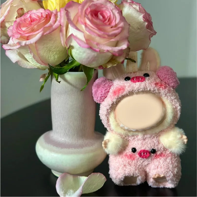 Pink crochet piggy doll outfit pattern on a plush doll standing beside a white vase with pink roses