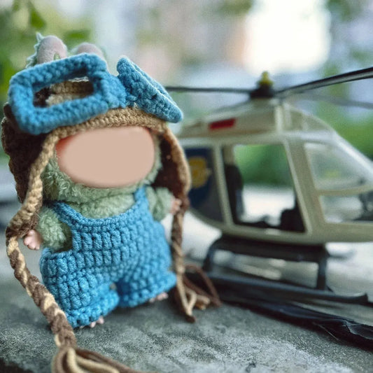 Cute handmade crochet pilot hat pattern on small doll wearing blue overalls next to toy helicopter