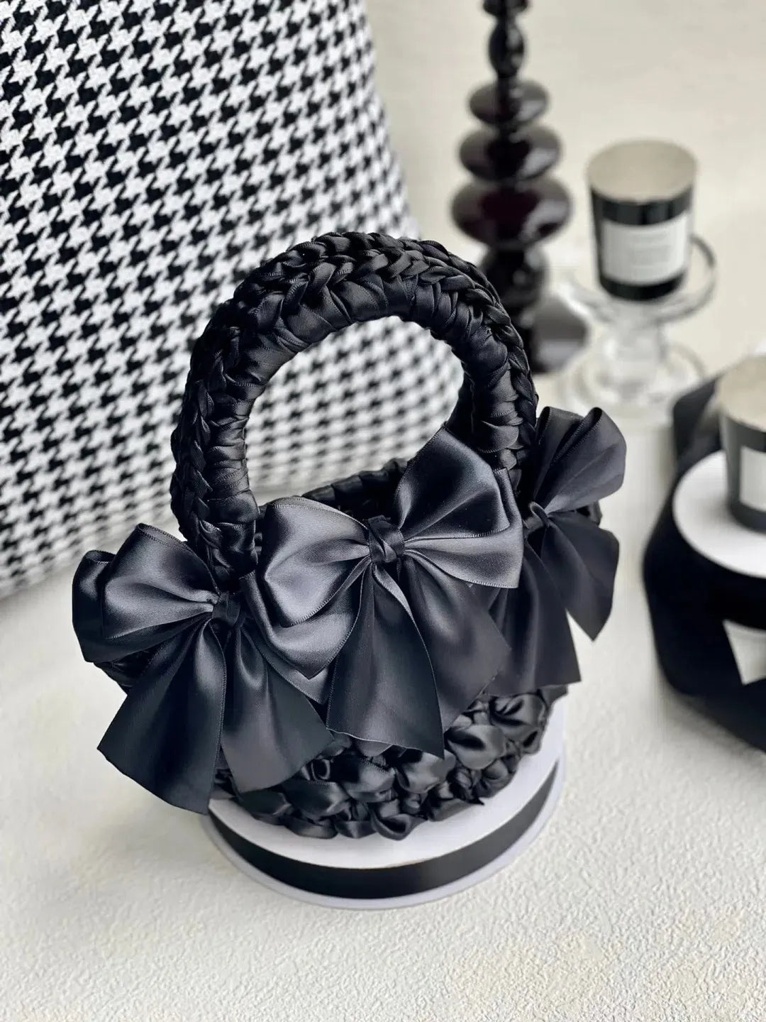 DIY bow adorned purse in black with large satin bows and braided handle displayed on a round platform