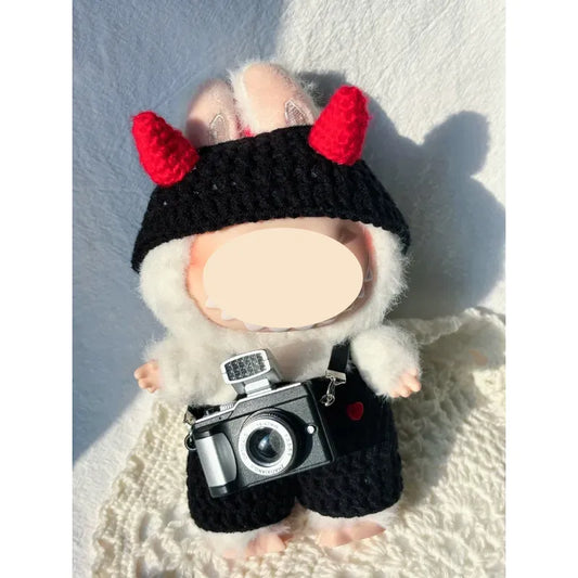 DIY crochet devil costume with red horns and black outfit on a plush doll holding a toy camera
