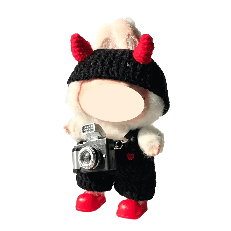 DIY crochet devil costume with red horns and black outfit on a plush figure holding a camera