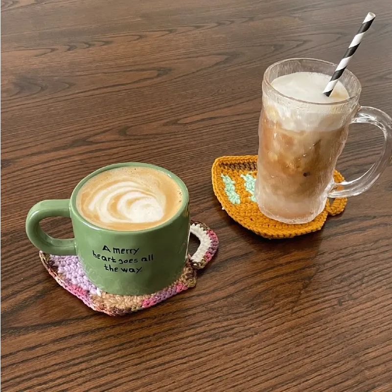 Two beverages on wooden table placed on FREE|beginner crochet cup coaster in pink and orange colors