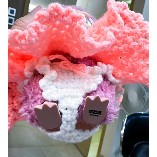 Close-up of a handmade crochet doll wearing a pink and white skirt featuring free-crochet doll panties pattern