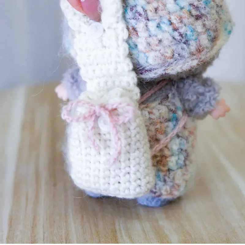 Handmade small white crochet bag shown as part of free doll accessories crochet pattern by The Knit Krazy