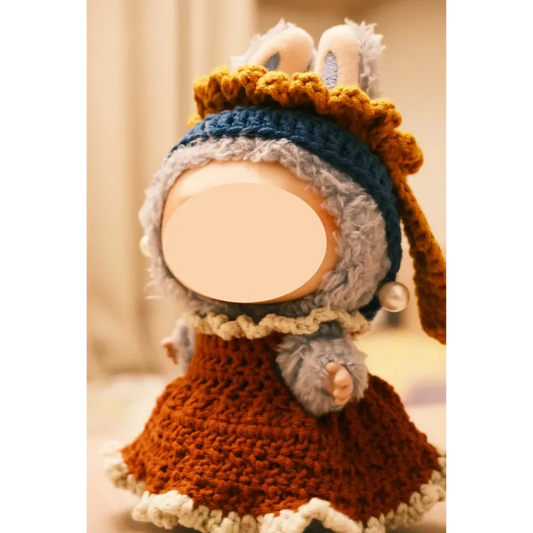 Handmade crochet girl with pearl earring doll clothes in warm tones including brown dress and blue bonnet