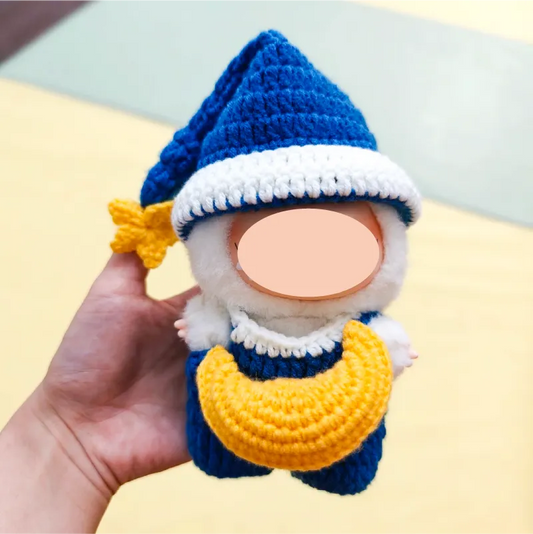 Hand holding a blue and white crocheted gnome doll with a yellow crescent moon on the front