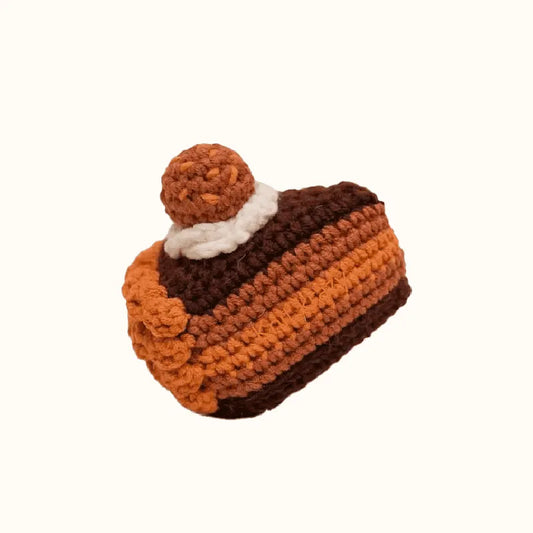 Handmade crochet chocolate cake pattern with layers of brown and orange yarn and a small ball on top