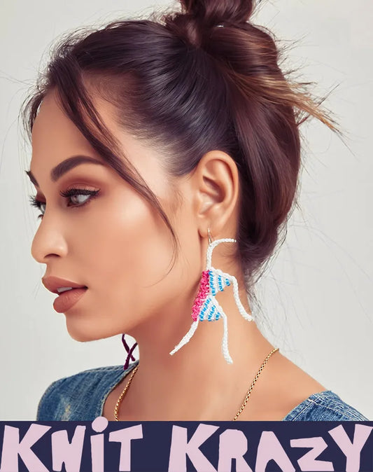 Handmade crochet earrings in blue pink and white worn by woman with brown hair in a bun