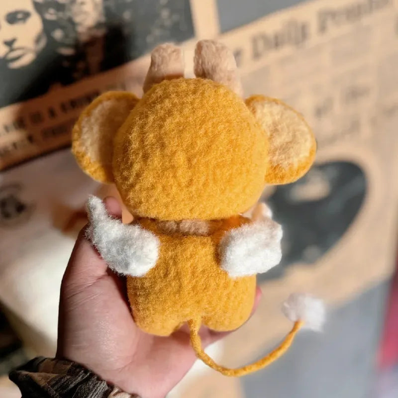 Hand holding a small plush toy dressed in a yellow crochet monkey outfit pattern with ears and a tail