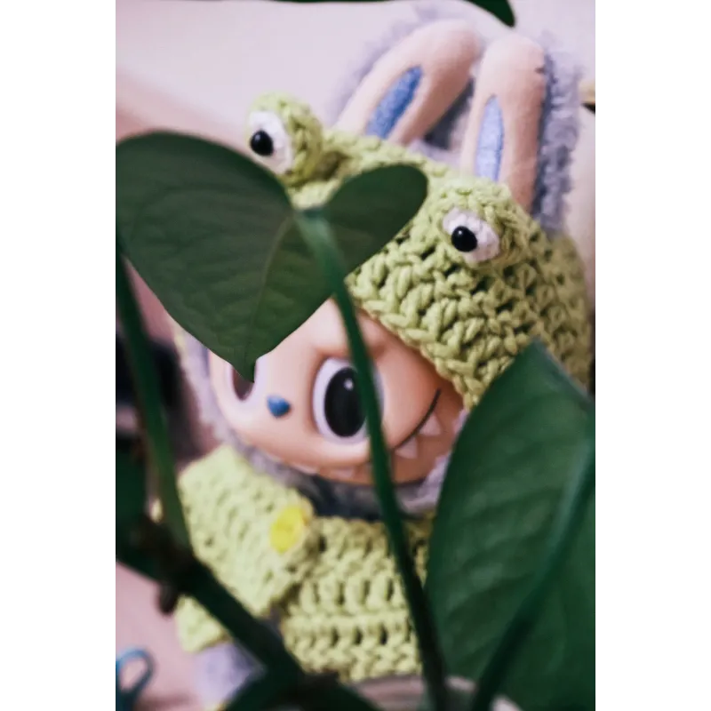 Cute bunny doll wearing a green frog knit doll outfit with big eyes knitted on the hood