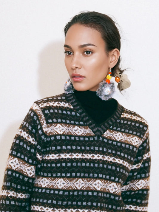 Handmade hedgehog keychain hanging from woman's ear with colorful beads and pom poms