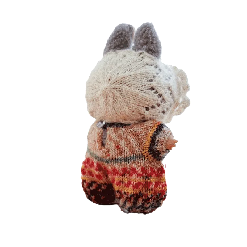 Hand-knitted doll wearing colorful knitted doll romper pattern from redbook shown from the back
