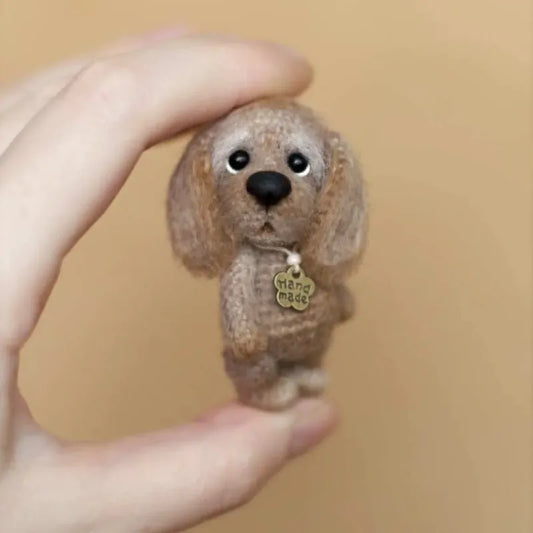 Hand holding a small brown mini crochet puppy pattern with a handmade tag on a beige background