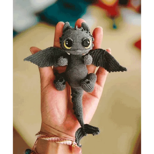 Hand holding a handmade Toothless crochet gift with detailed wings and big eyes