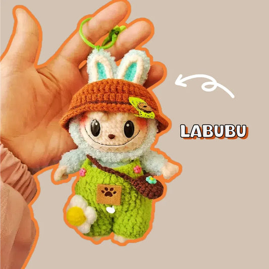 Hand holding a bunny crochet keychain pattern with green overalls and brown hat keychain