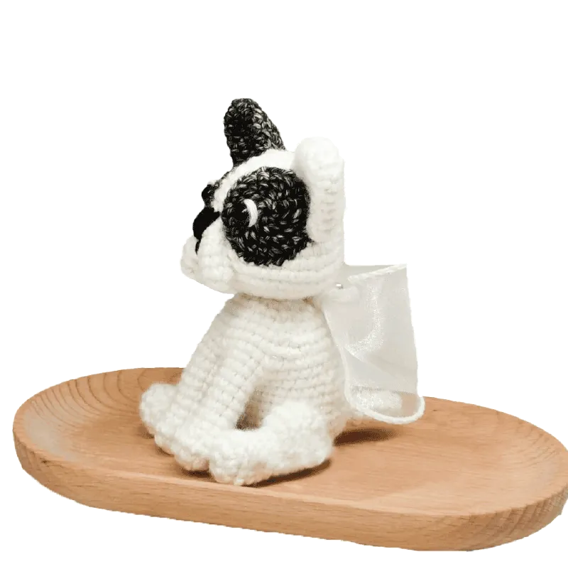 Handmade crochet French bulldog made with black and white yarn on a wooden tray crochet french bulldog pattern