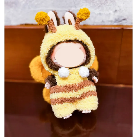 Plush doll dressed in playful bee knitwear for dolls with yellow and brown stripes and pompom antennae