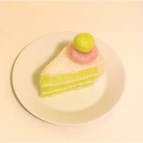 Melon grape dessert crochet pattern showing a slice of crocheted cake with green and pink yarn decoration on a white plate