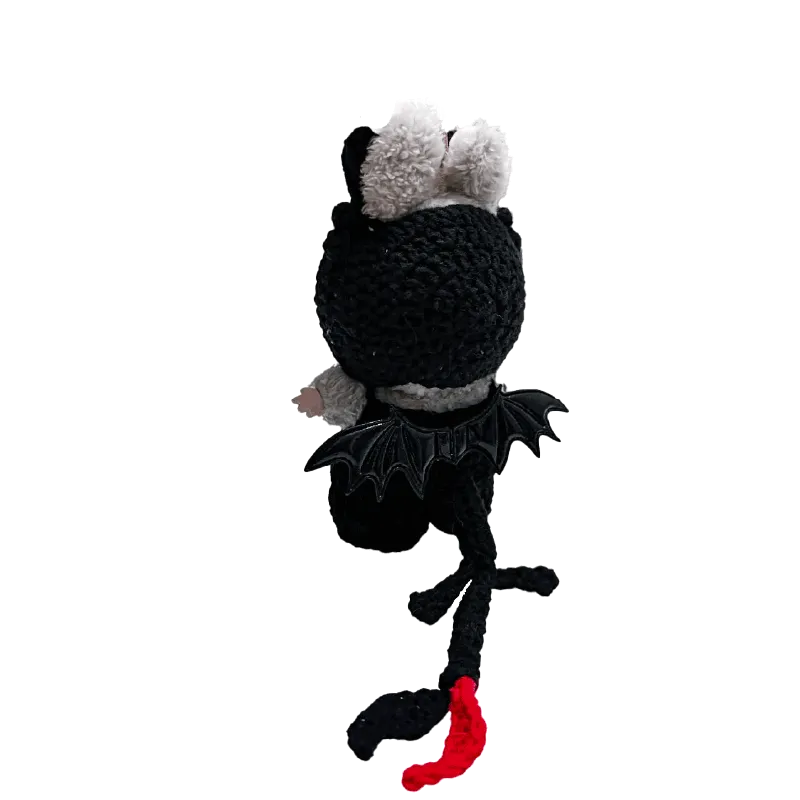 Handcrafted black and white amigurumi toy featuring night dragon crochet pattern with bat wings and red tail tip