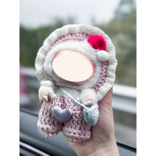 Hand holding redbook pink knit doll outfit with heart detail and small blue pouch