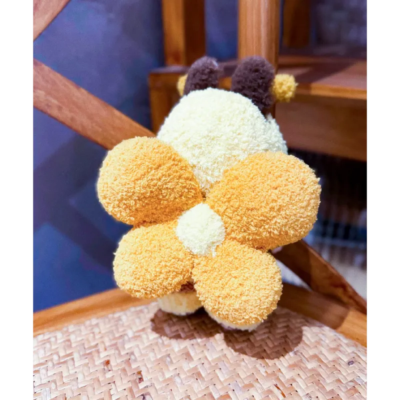 Back view of playful bee knitwear for dolls featuring soft textured yellow and brown yarn wings and antennae