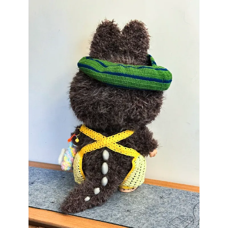 Back view of a plush toy wearing a Zimomo crochet outfit pattern with yellow shorts and green headband