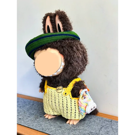 Handmade plush bunny wearing a yellow crocheted outfit with a green visor hat using Zimomo crochet outfit pattern
