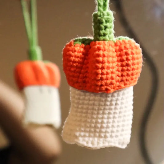 Crocheted pumpkin and carrot decorations on a blurred background