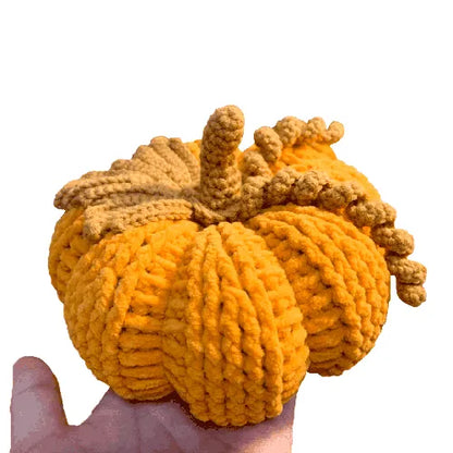 Knitted pumpkin toy held in a hand against a white background