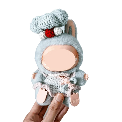 Hand holding a doll dressed in a gray chef costume crochet pattern for dolls with a chef hat and pink details