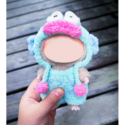 Hand holding a plush toy wearing a colorful clown fish crochet pattern outfit with blue and pink details