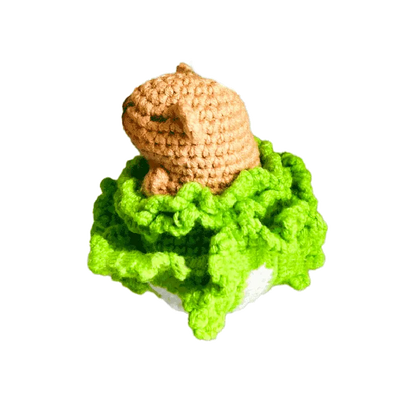 Handmade crochet capybara pattern featuring a light brown capybara resting on bright green textured yarn