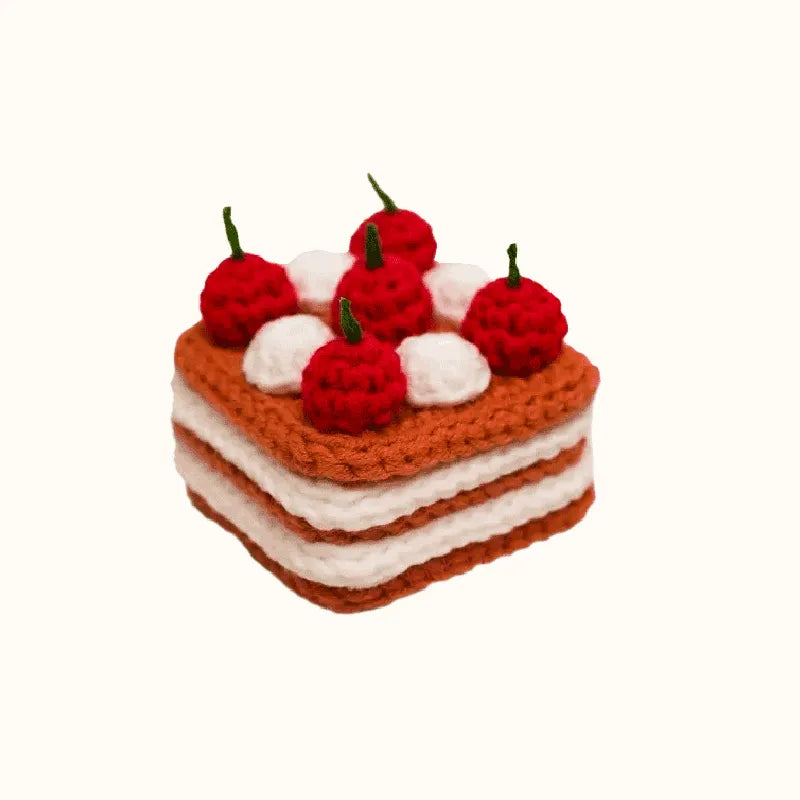 Crochet cherry cake pattern featuring a layered square cake with red cherries and white cream dollops