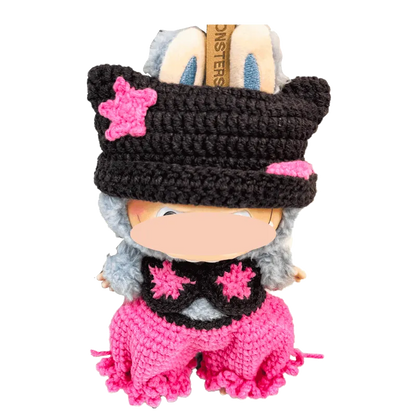 Handcrafted crochet doll wearing a black hat with pink stars and matching pink pants by The Knit Krazy