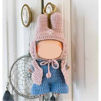 Handmade crochet keychain doll wearing a pink bunny hat and blue outfit by The Knit Krazy