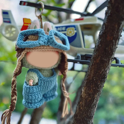 Handmade crochet doll wearing blue crochet pilot hat pattern and overalls hanging near toy helicopter